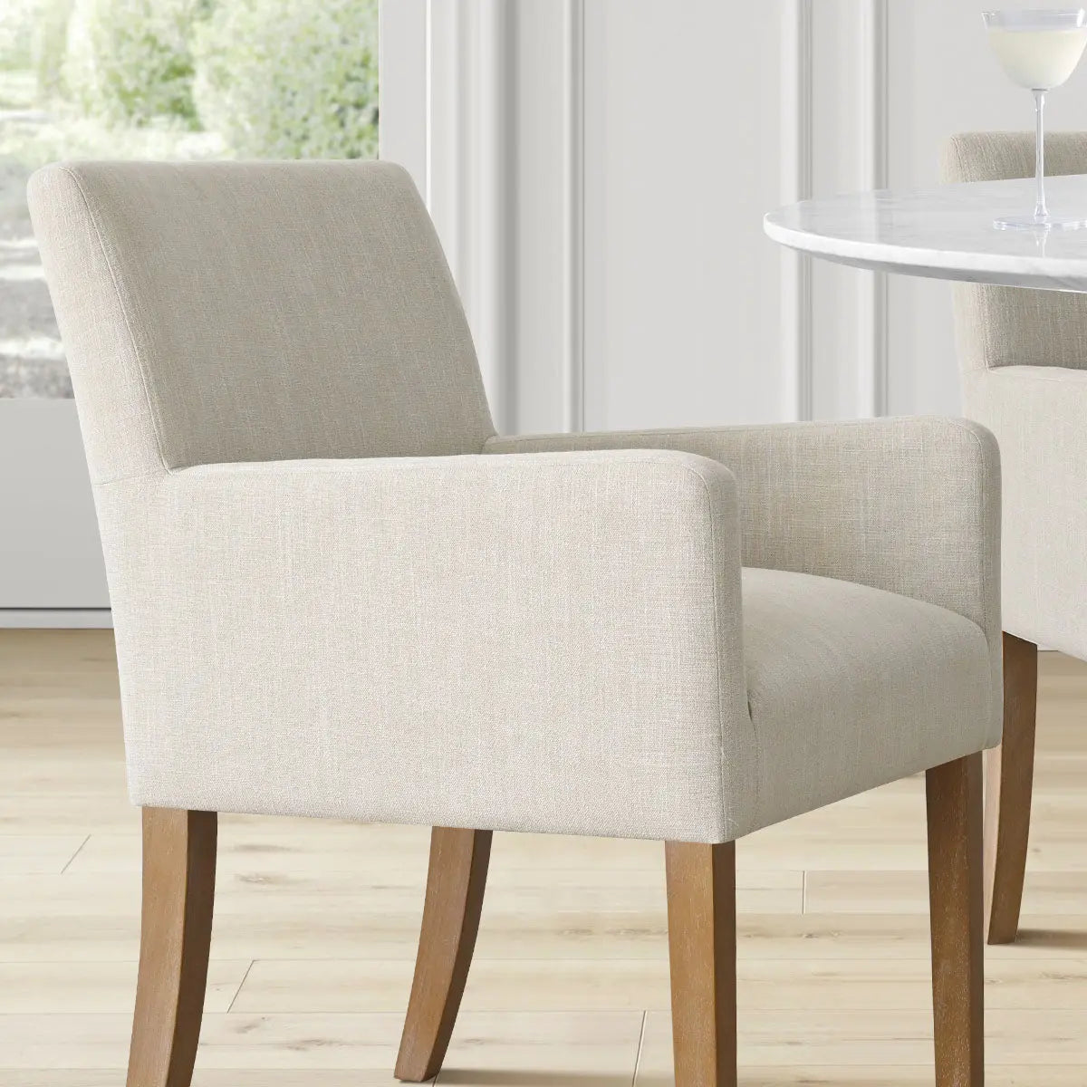 North Modern Boucle Upholstered Armchair in dining room with wood flooring and white panel walls.