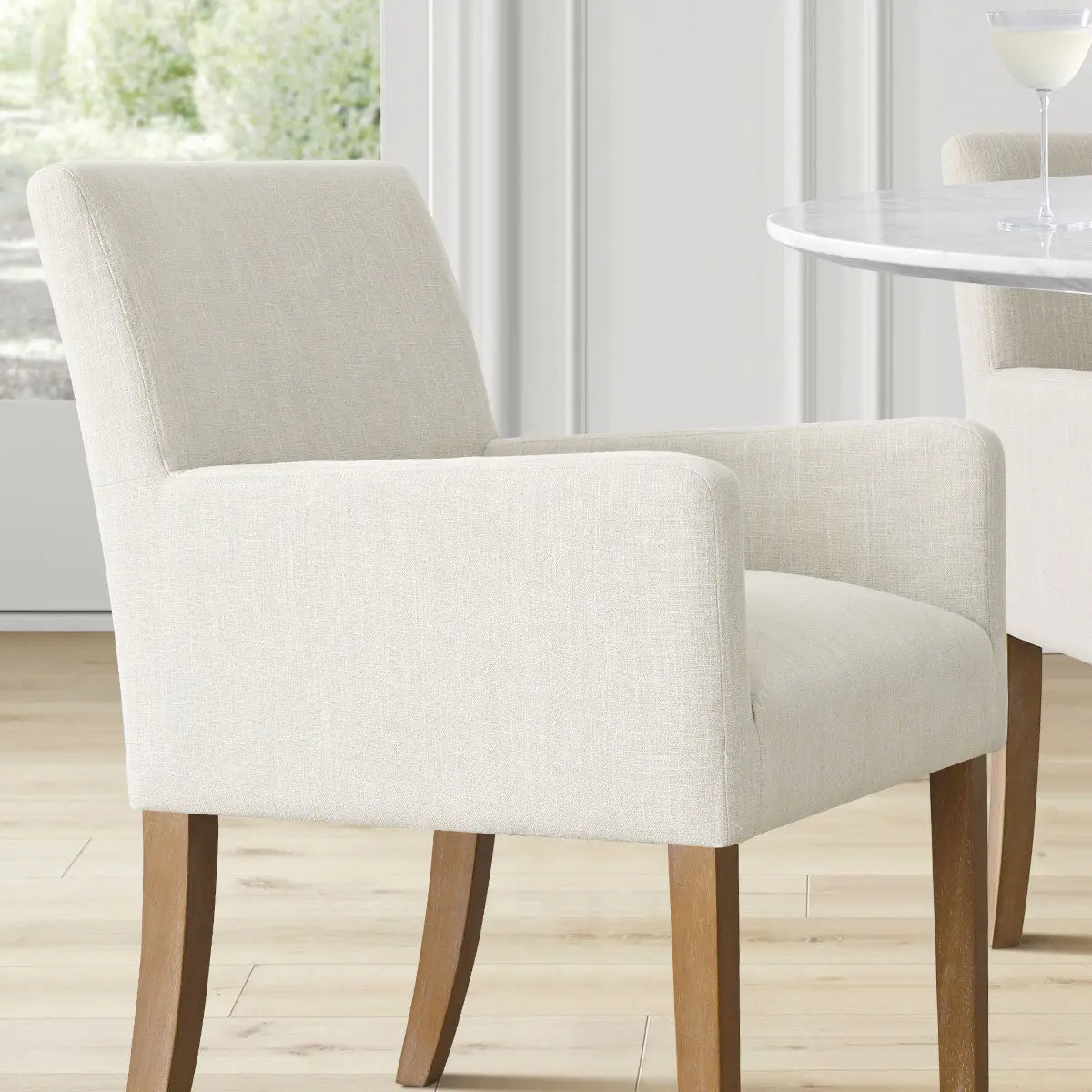 North Modern Boucle Armchair, light wood flooring, elegant white wall, round marble table, dining room.