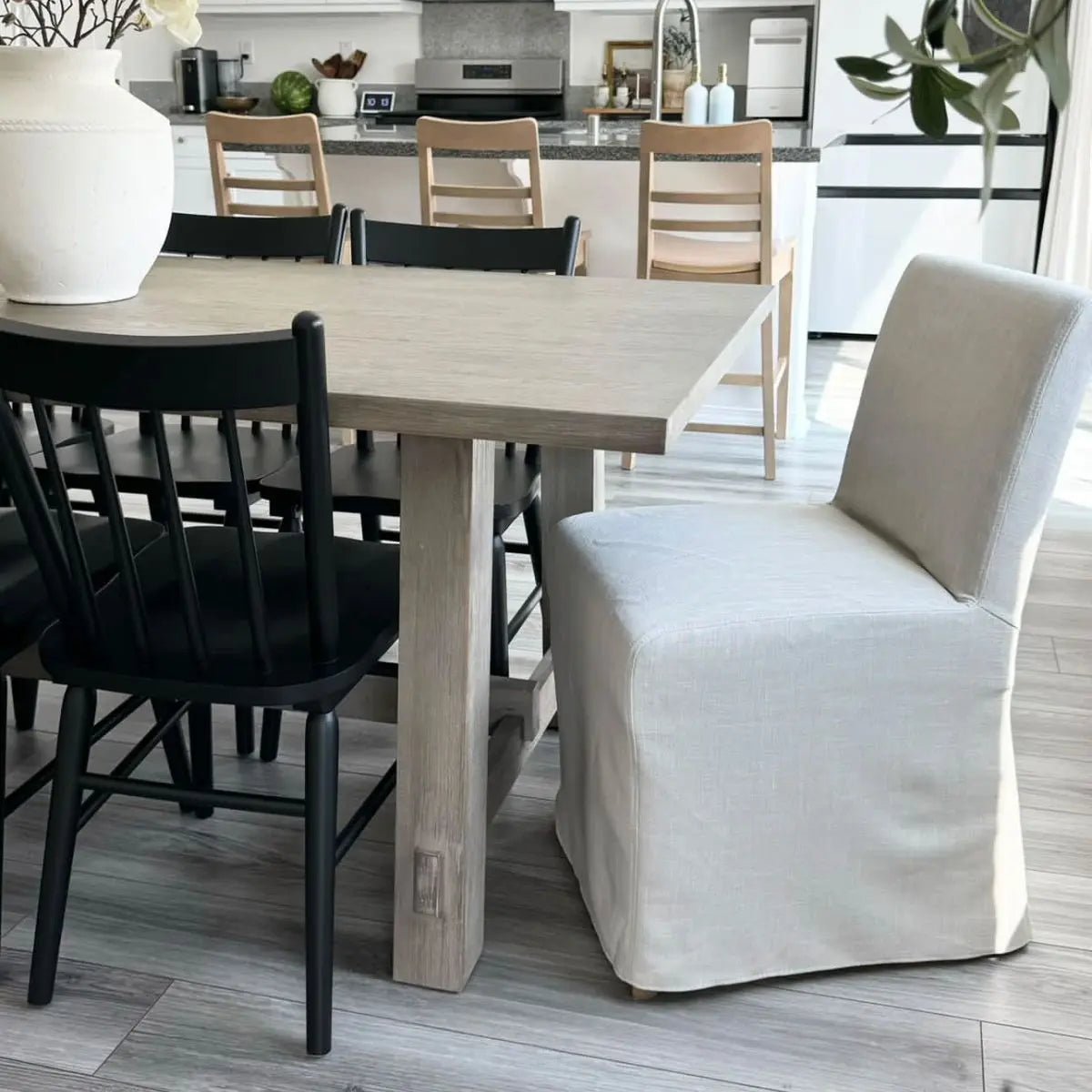 North Beige dining chair set with slipcovers, light wood table, black chairs in modern dining room.