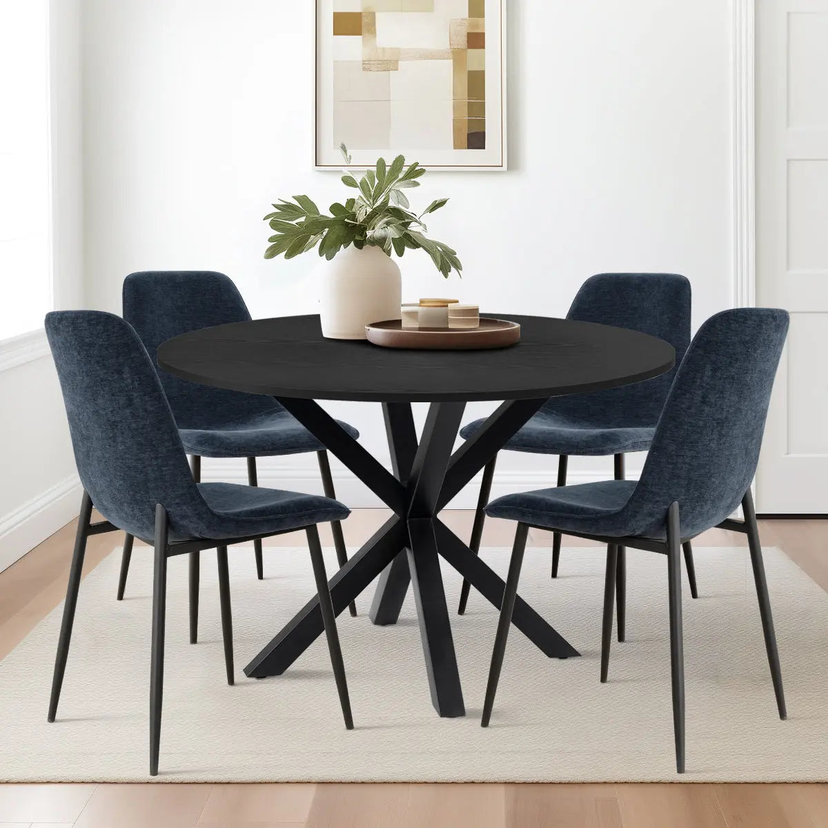 Oliver & Oslo Round Dining Table Set in modern dining room with blue chairs and wooden flooring.