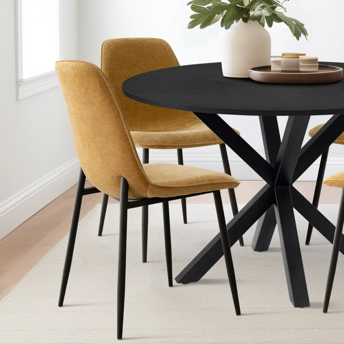 Oliver & Oslo round dining table set with mustard chairs, placed on light carpet in dining room.