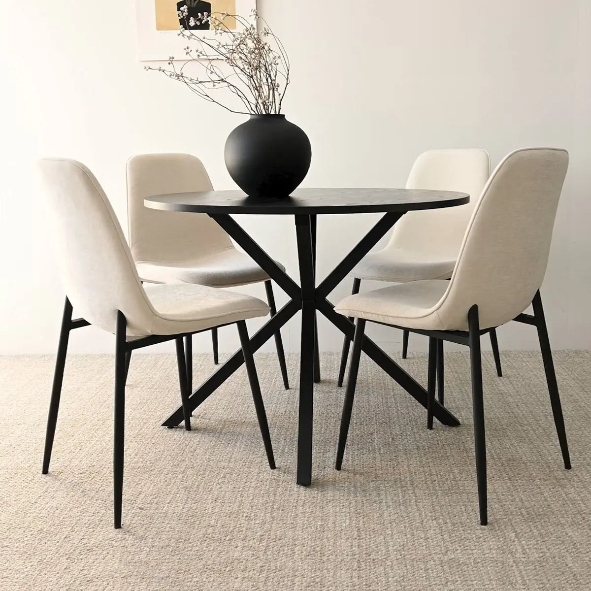 Oliver & Oslo dining table set with beige chairs, black vase, neutral wall, carpeted flooring.