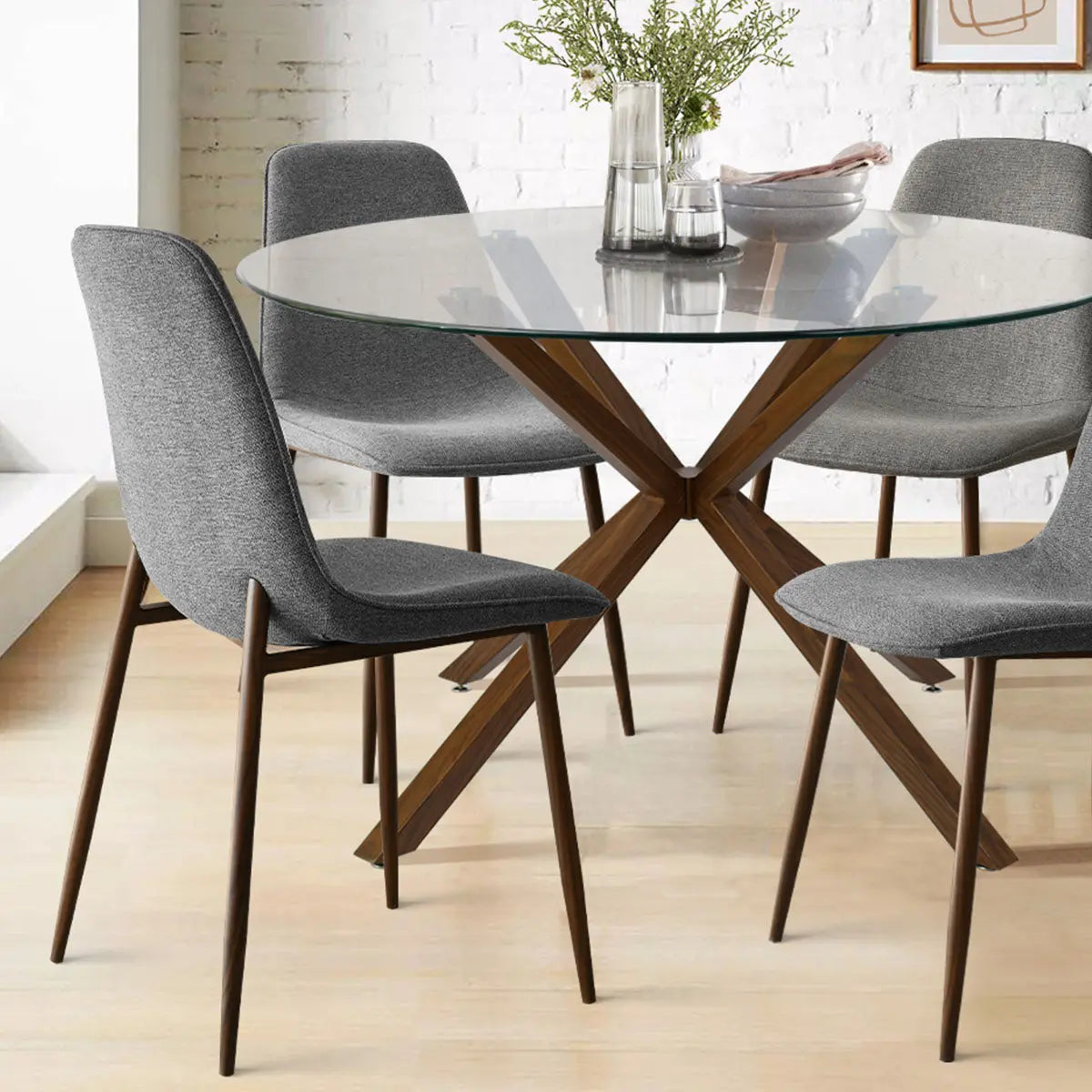 Oliver & Oslo dining table with grey chairs, brick wall, light wood floor in modern dining room.