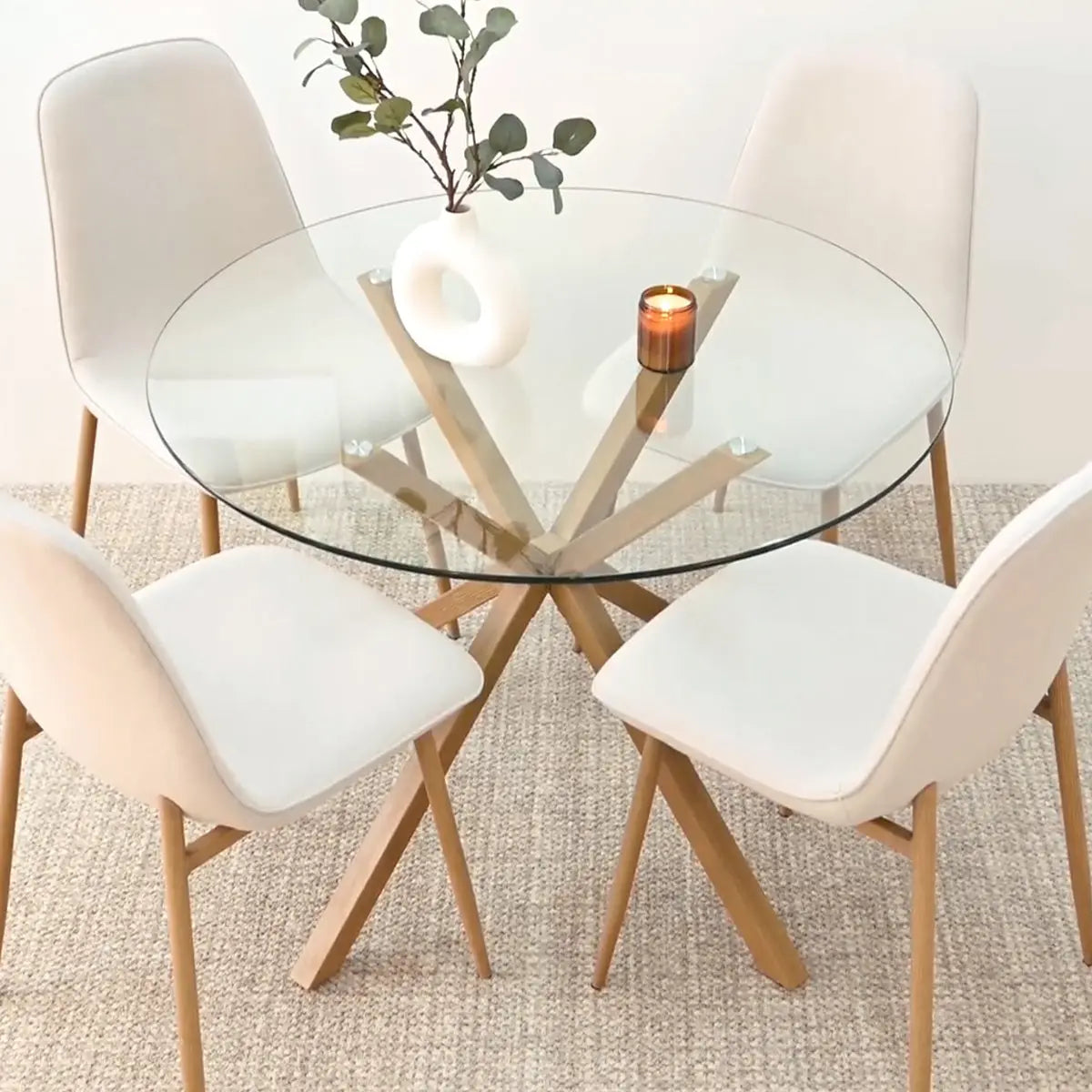 Oliver & Oslo dining set, glass round table, four beige chairs, light carpet, dining area.