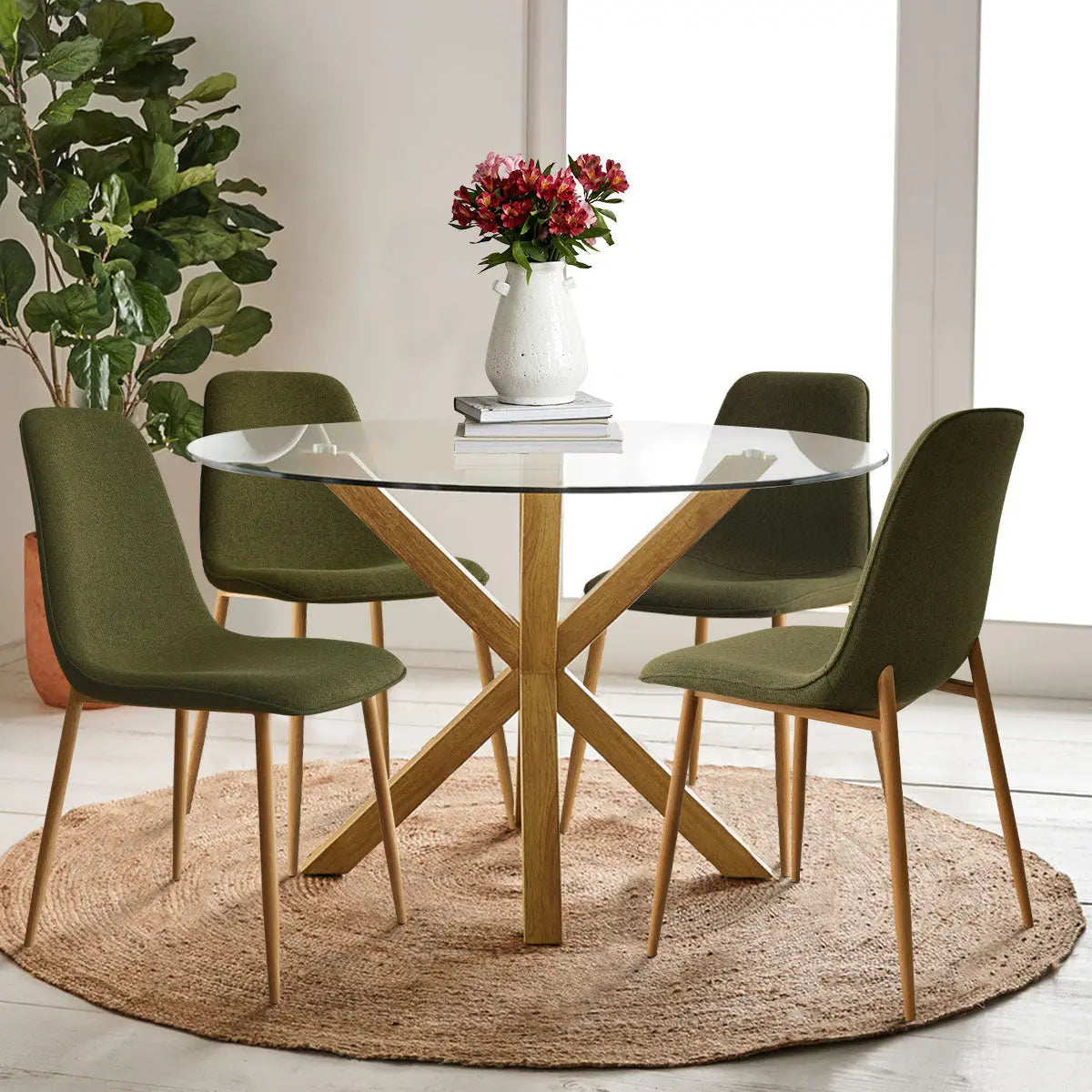 Oliver & Oslo dining table set with green chairs, glass top, wooden legs, jute rug, white walls.