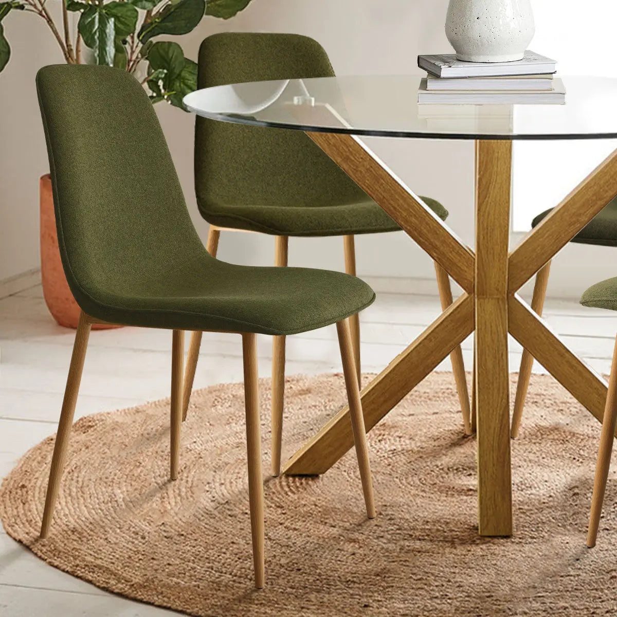 Oliver & Oslo dining set, glass top, wood legs, green chairs, neutral room, beige rug, white floor.