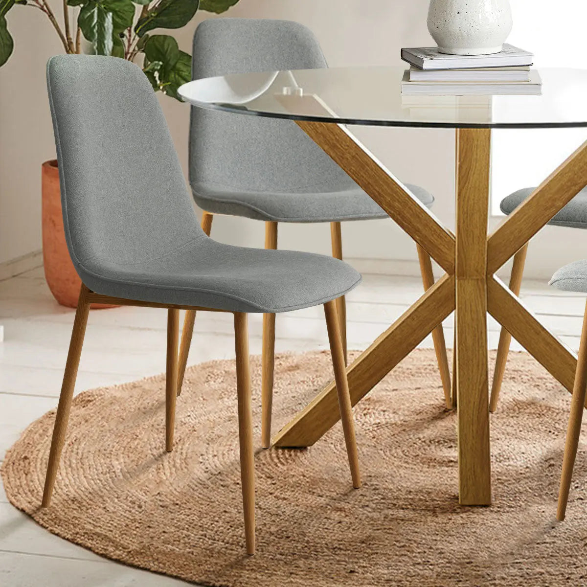 Oliver & Oslo Glass Round Dining Table Set with gray chairs, light wood flooring, round rug.