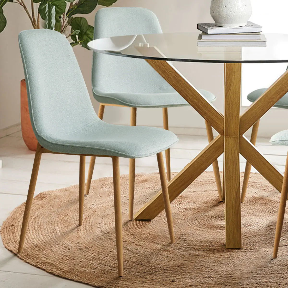 Oliver & Oslo Glass Round Dining Table Set, light blue chairs, round rug, wooden floor, indoor.