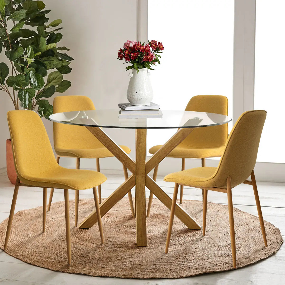 Oliver & Oslo glass round dining table set with yellow chairs on rug in bright dining room.