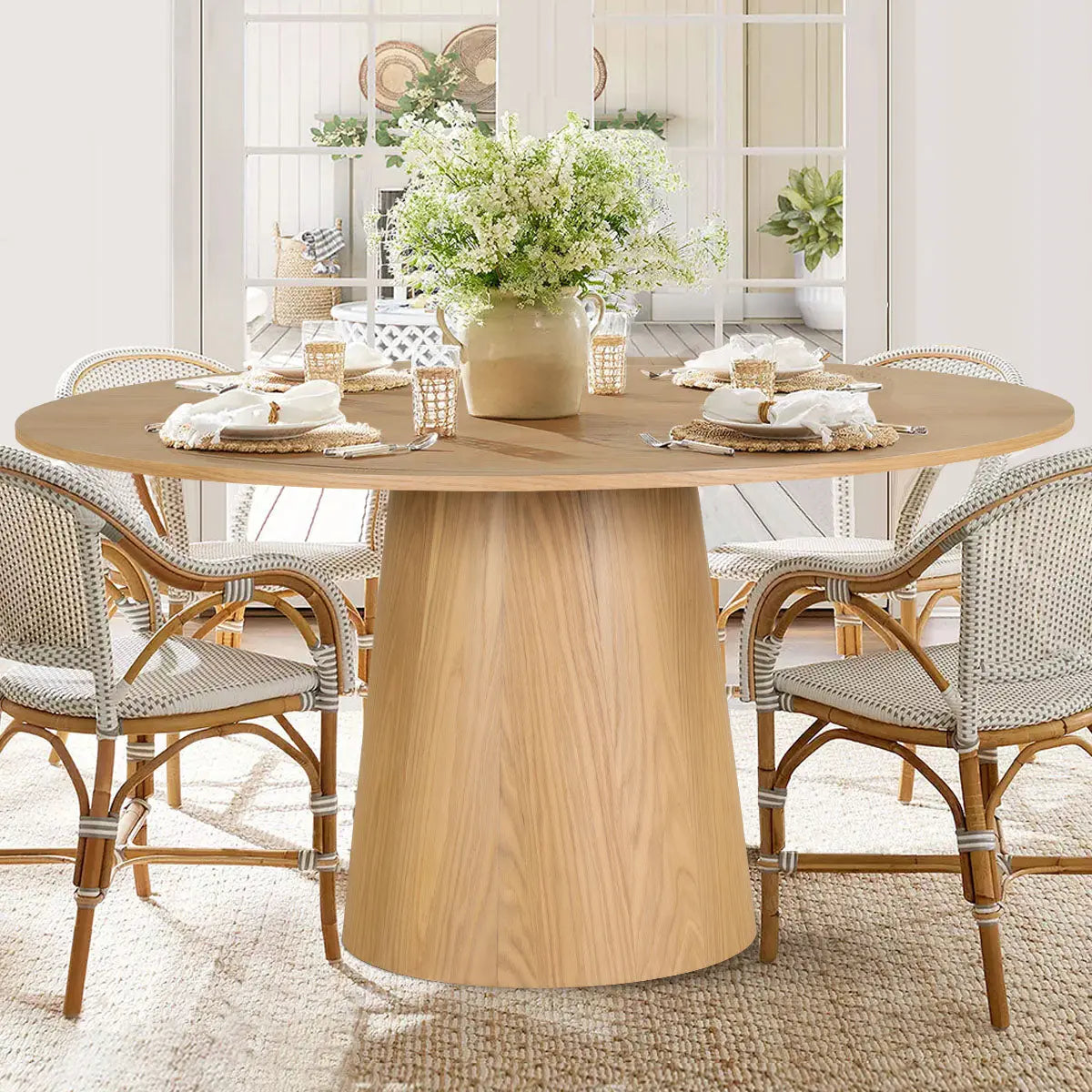 Orchid Oak dining table with wicker chairs in bright dining space, natural rug flooring.