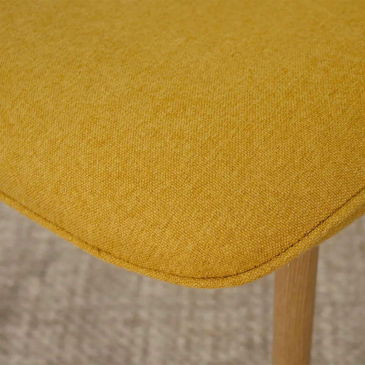 Close-up of Oslo Modern Chenille Upholstered Dining Chair in mustard, showing oak leg detail.