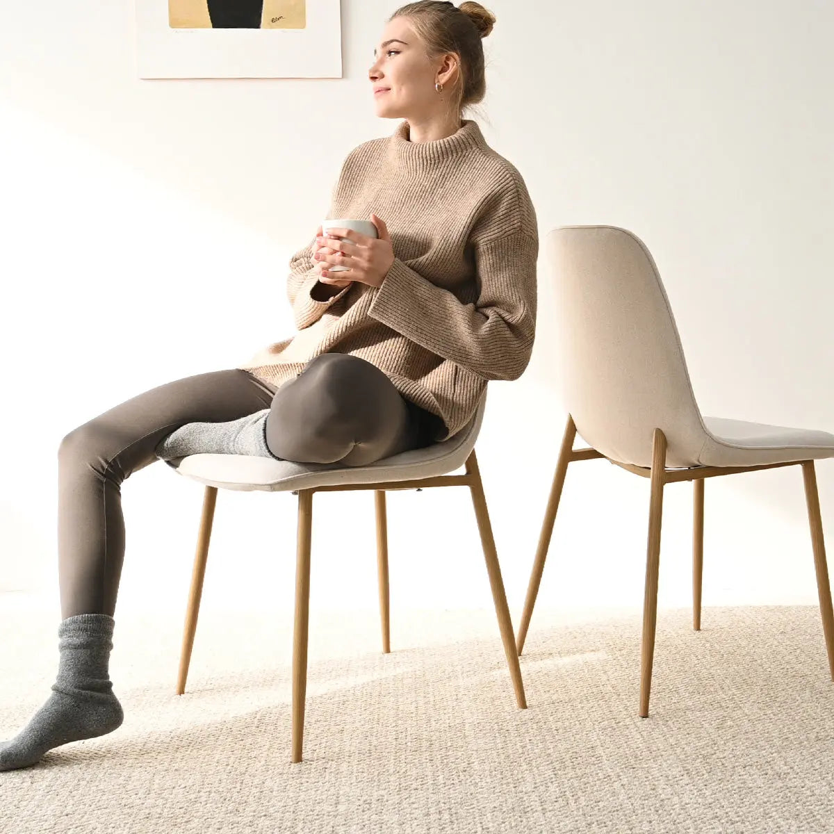 Oslo Modern dining chair with oak legs, beige upholstery, in cozy carpeted room.