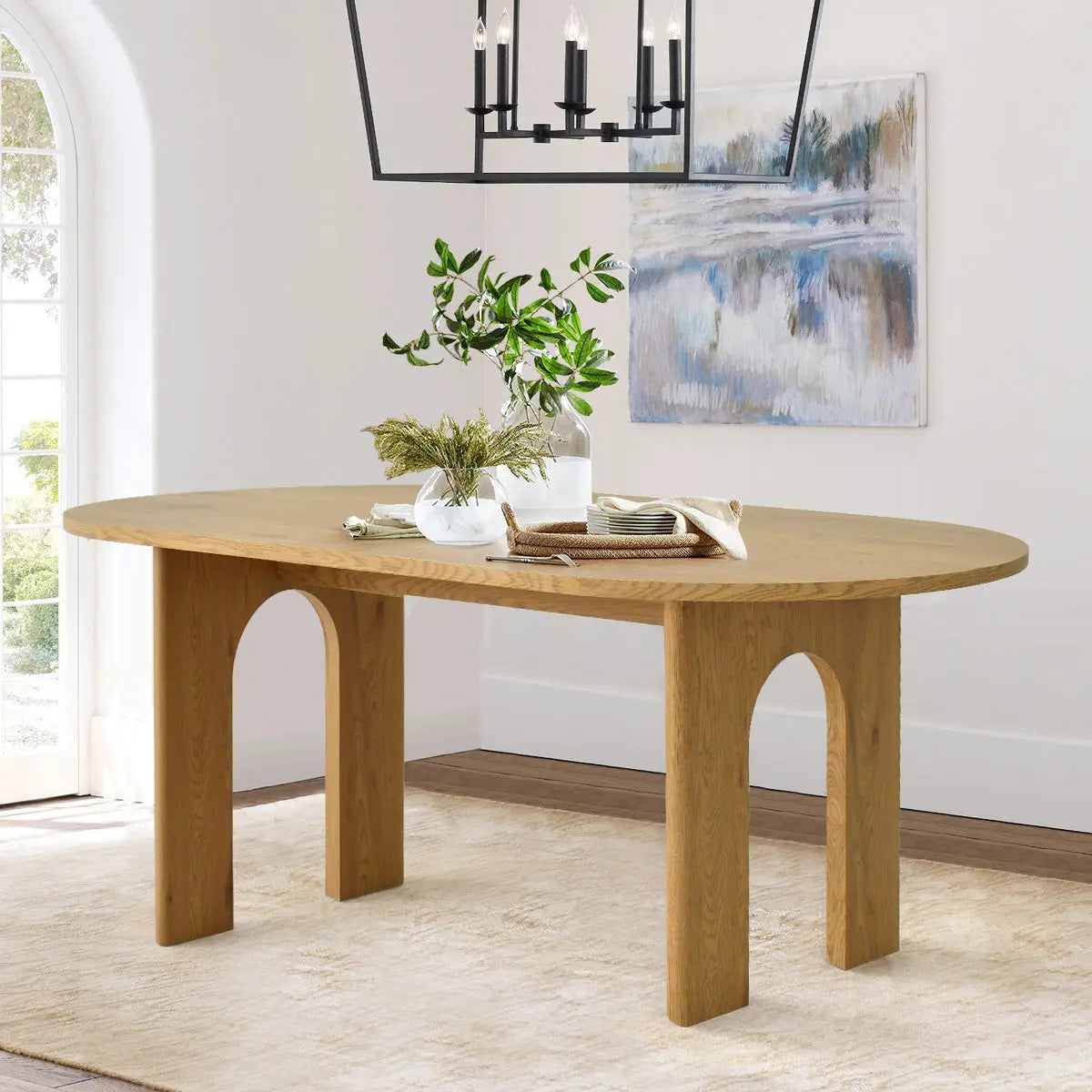 Modern oval dining table in a bright room, wood flooring, neutral wall, contemporary wall art.