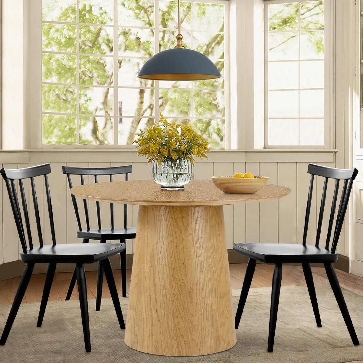 Saigong Oak Round Dining Table with black chairs, oak floor, white wall, pendant lamp, dining room.