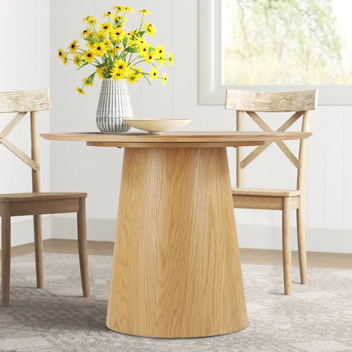 Saigong Oak Round Dining Table in modern dining room with light wood chairs and neutral rug.