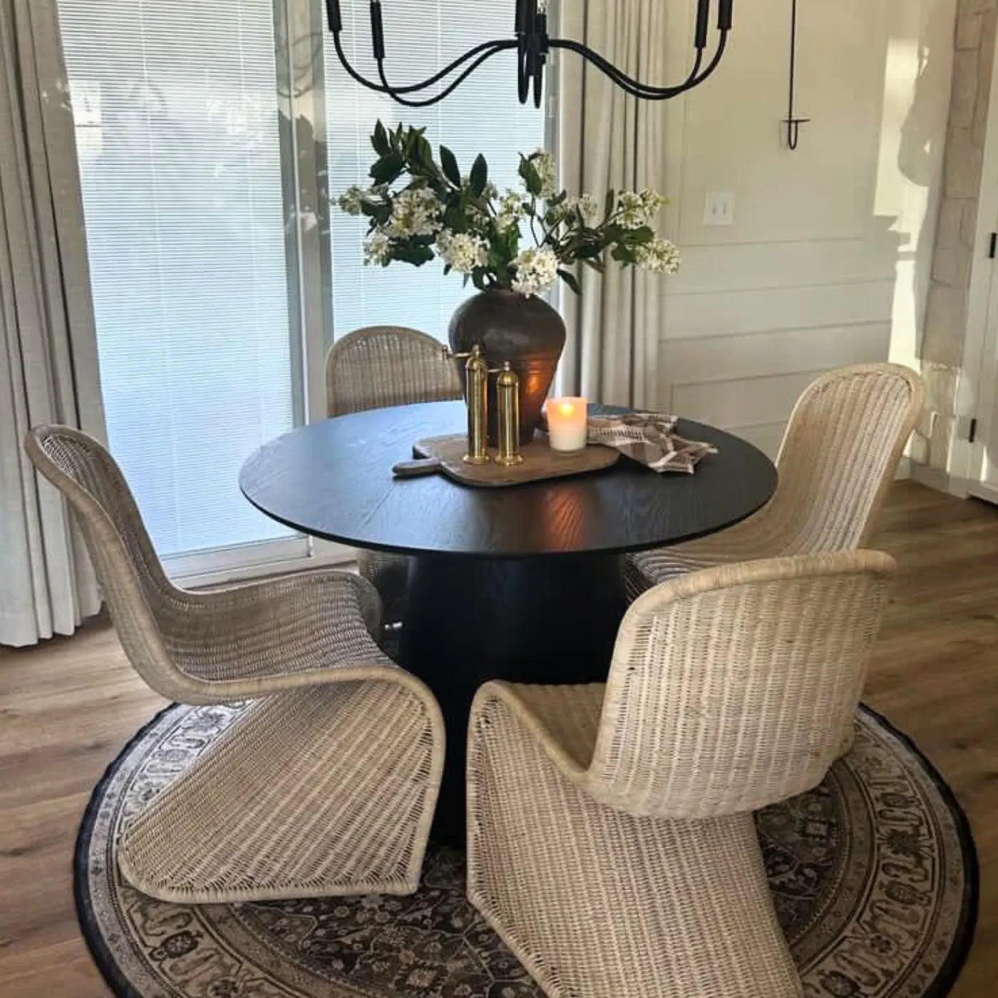 Saigong Oak Dining Table with wicker chairs on patterned rug in elegant dining room.