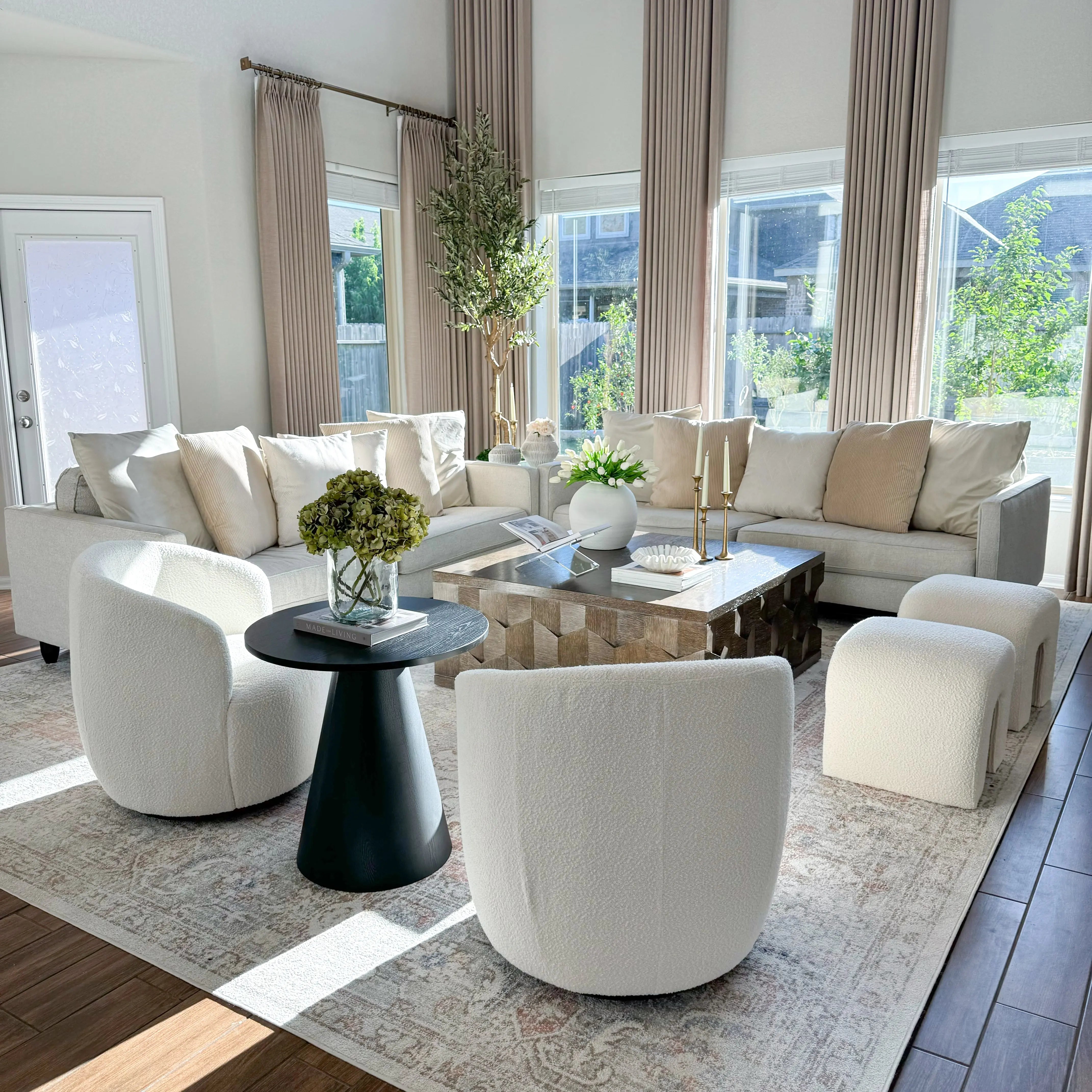 Bright living room with Dwen Black Round Side Table, white chairs, beige sofa, hardwood flooring.