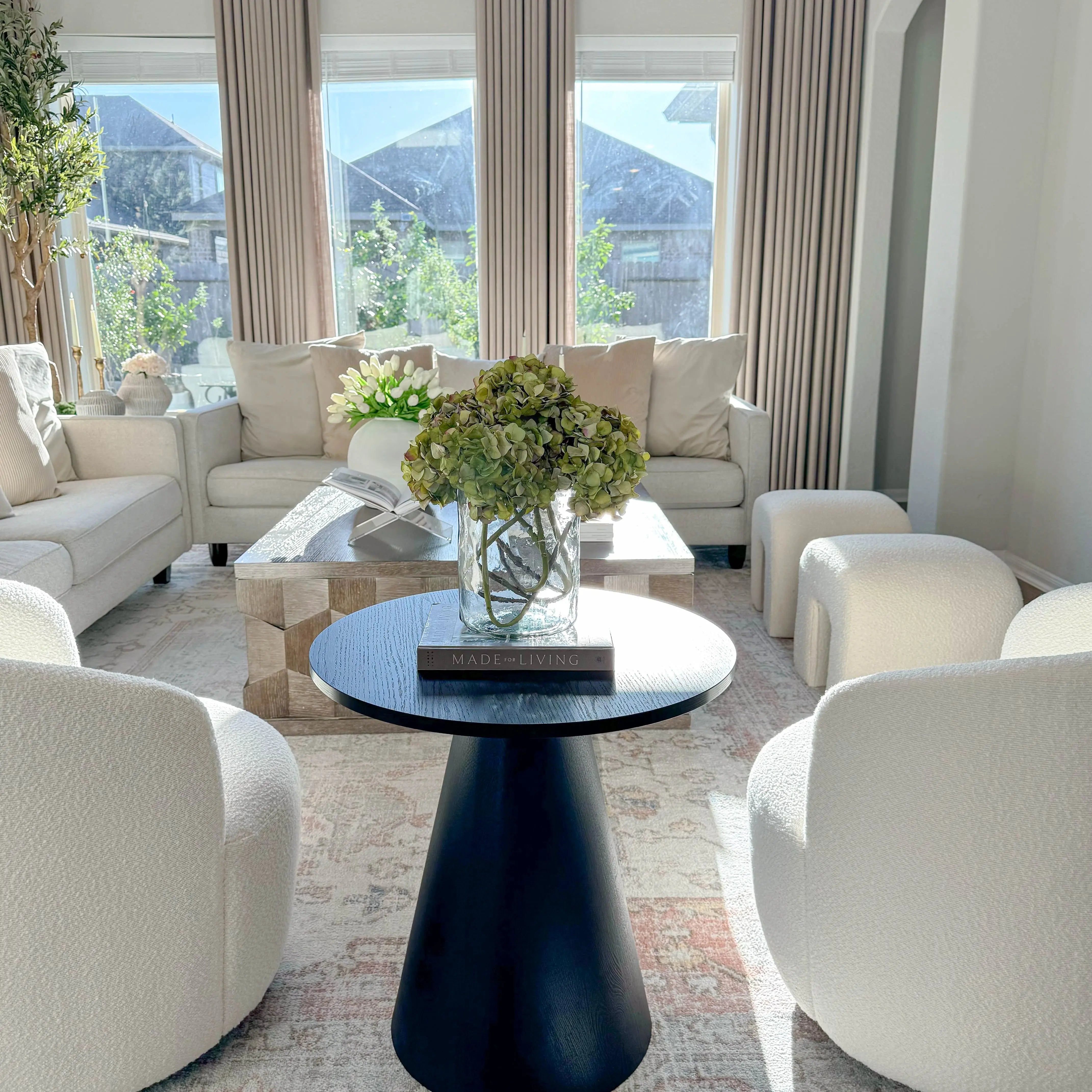 Dwen Modern Black Round Side Table in elegant living room, cream sofas, textured rug, large windows.