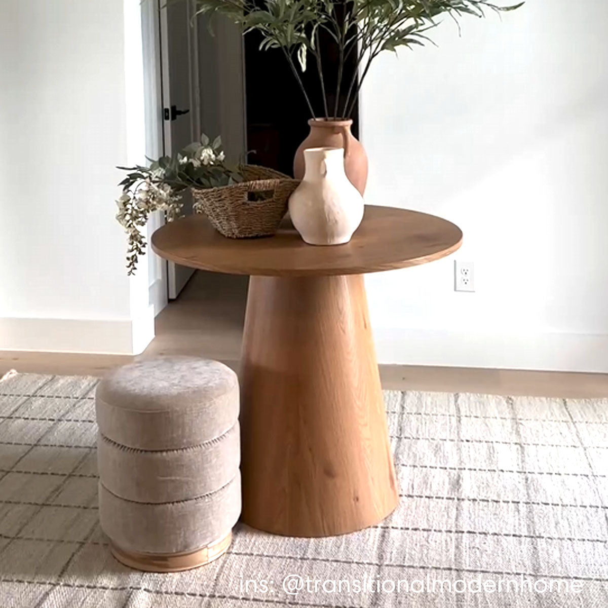 Dwen Modern Round Pedestal Dining Table in living room with beige stool and woven rug.