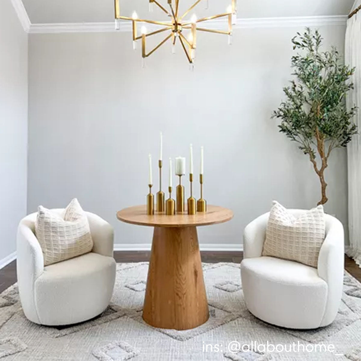 Dwen Modern Round Pedestal Console Table in cozy room with white chairs, gray walls, chandelier.