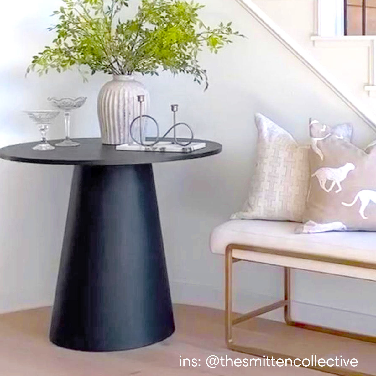 Dwen Modern Round Pedestal Console Table, light wood flooring, white wall, beige seating with cushions.