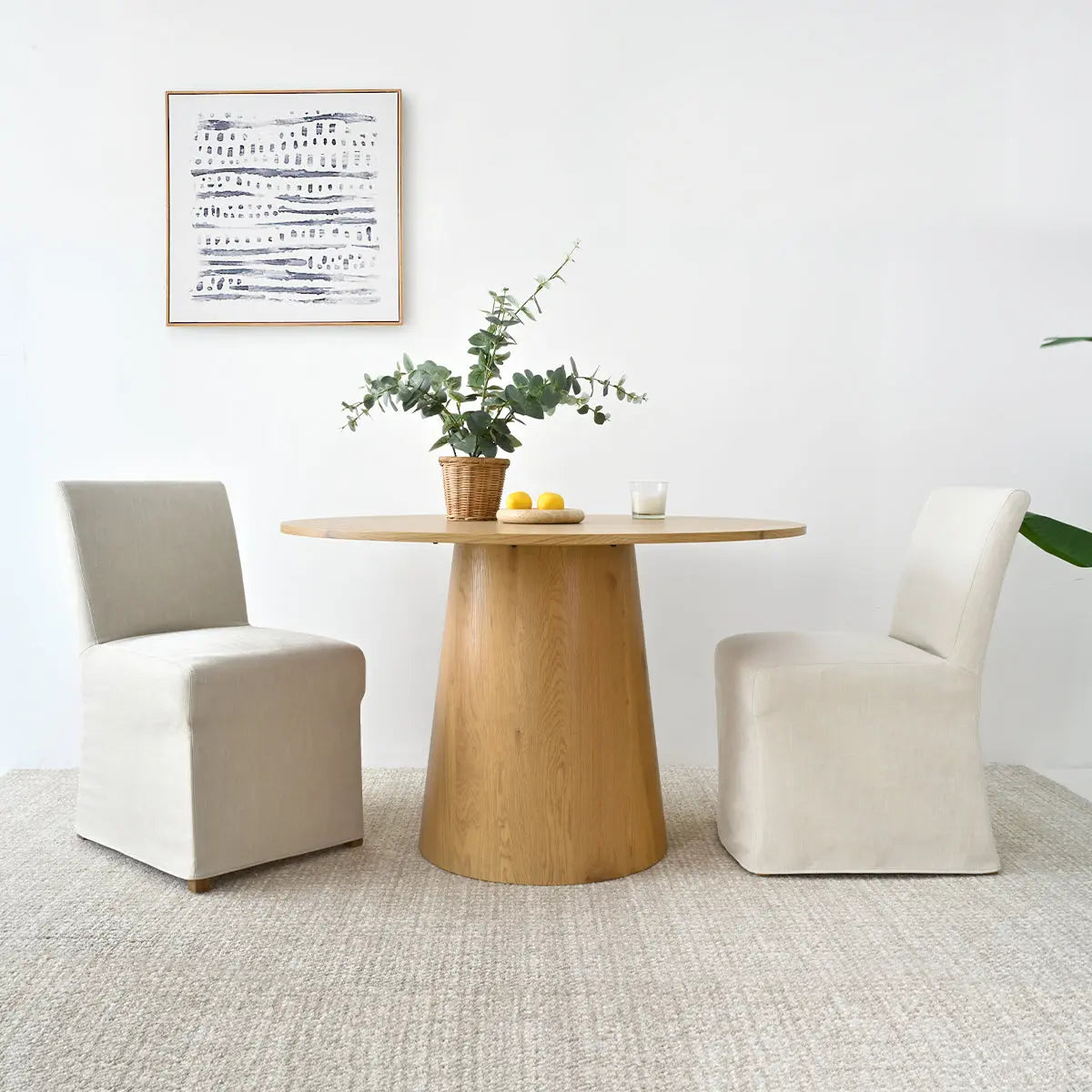 Beige dining chairs, wooden table, white walls, textured rug, modern dining room setting.