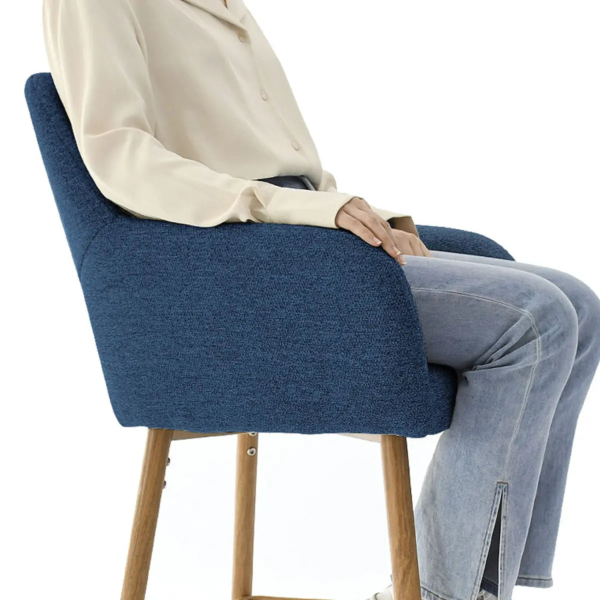 Blue upholstered counter stool with arms, wooden legs, modern design, person seated.