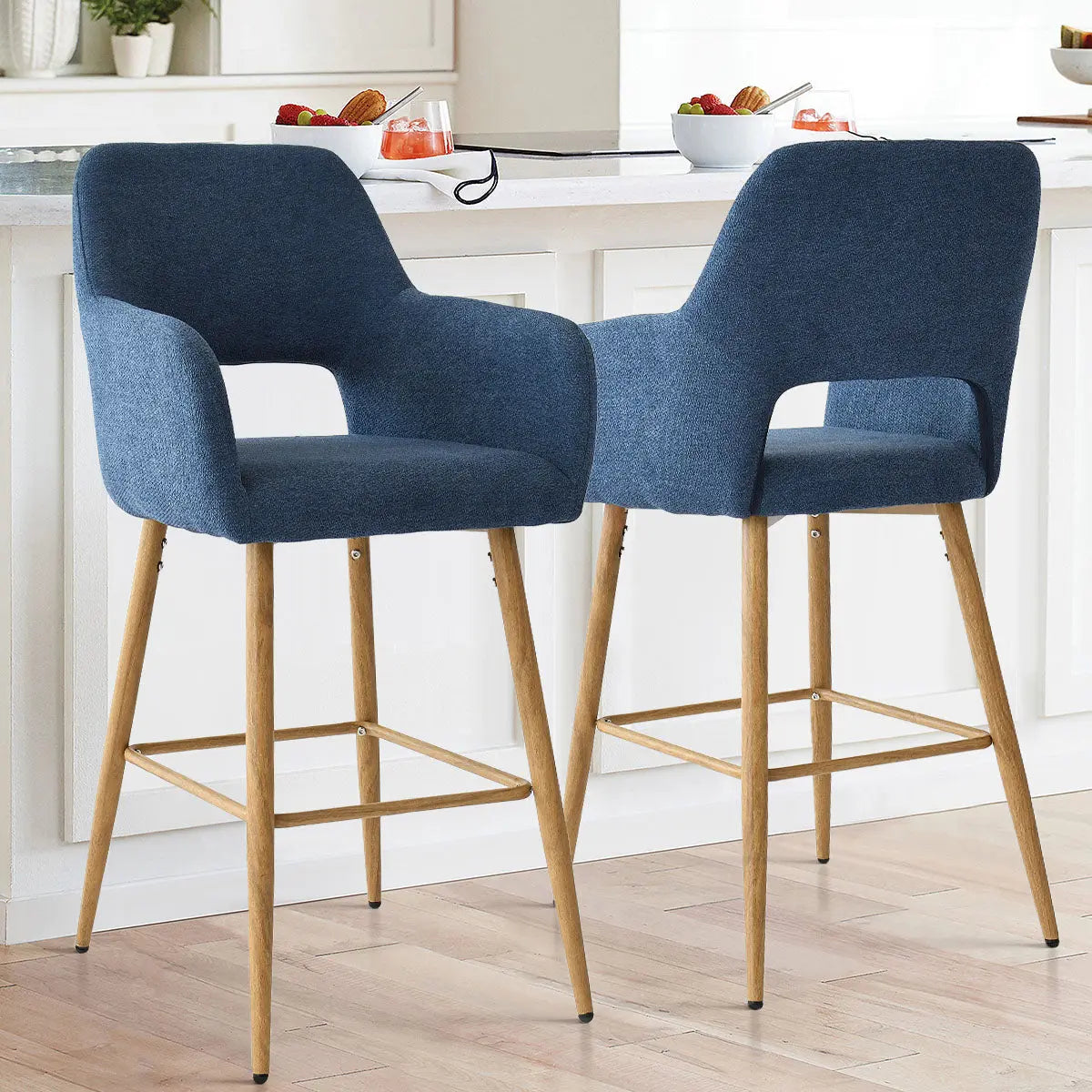 Blue Atlanta counter stools with arms, light wood legs, white kitchen island, bright modern room setting.