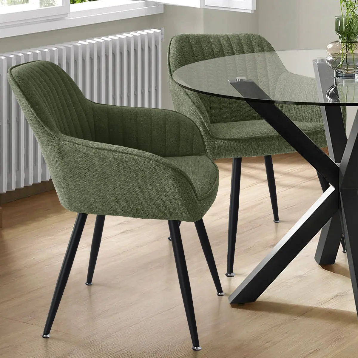 Green Boston Modern Upholstered Dining Chair with arms, glass table, wood flooring, gray walls, radiator.