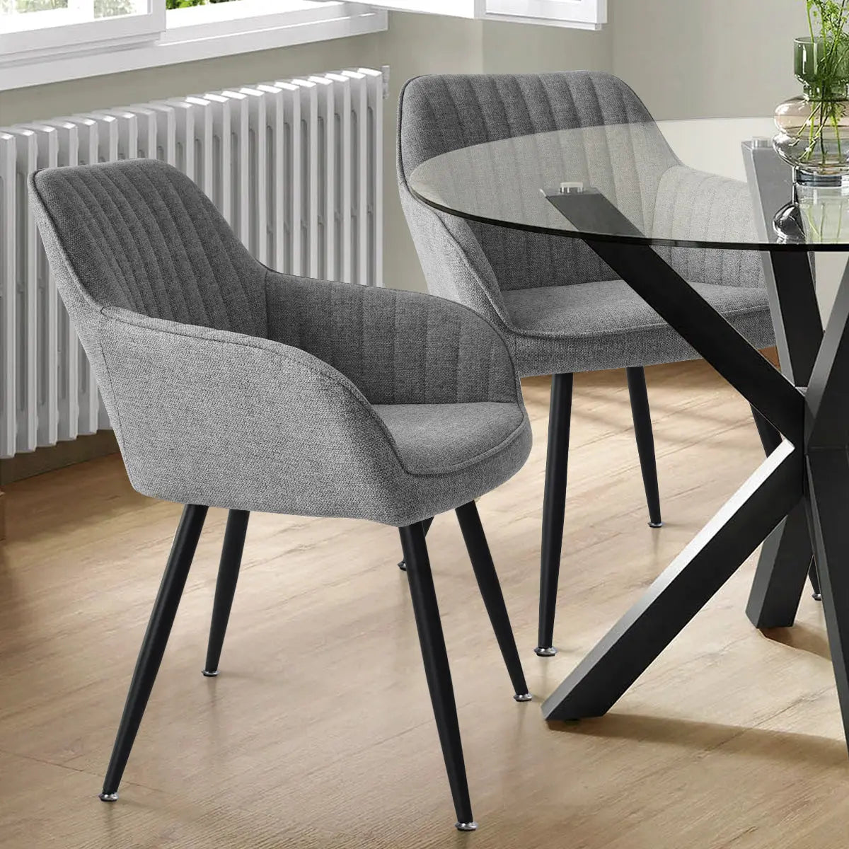 Gray Boston Modern Upholstered Dining Chair with Arms, wood flooring, black metal table in dining room.