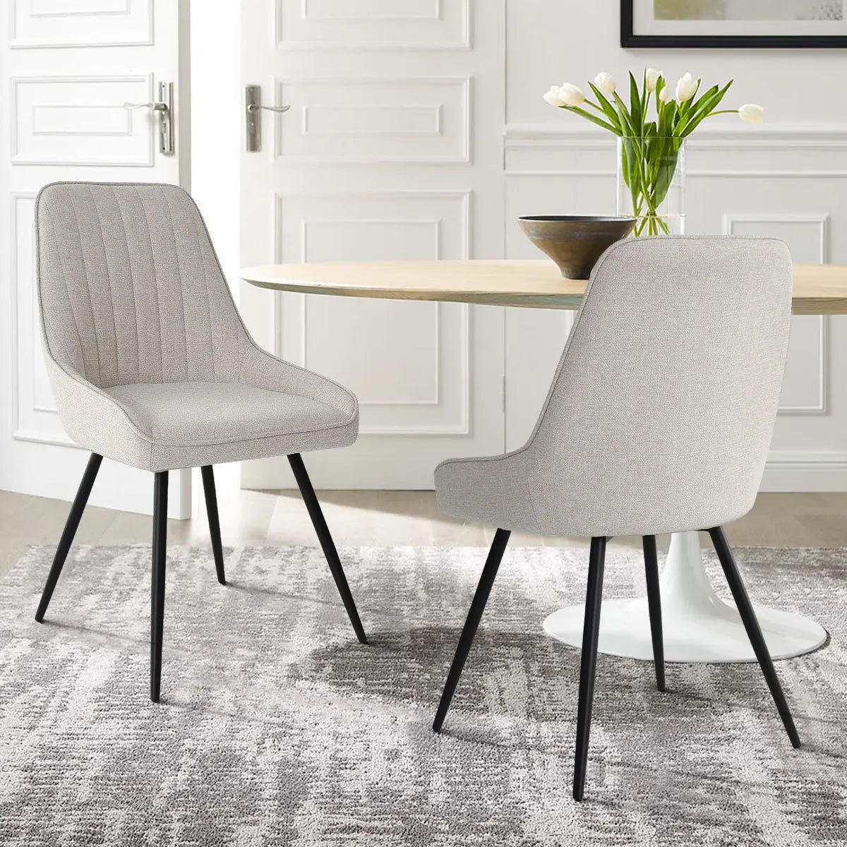 Boston Modern Upholstered Dining Chair in elegant room, light gray walls, round table, gray rug.