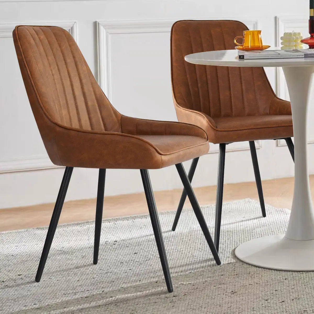 Boston Leather Dining Chairs with black legs, round white table, in a stylish dining room.