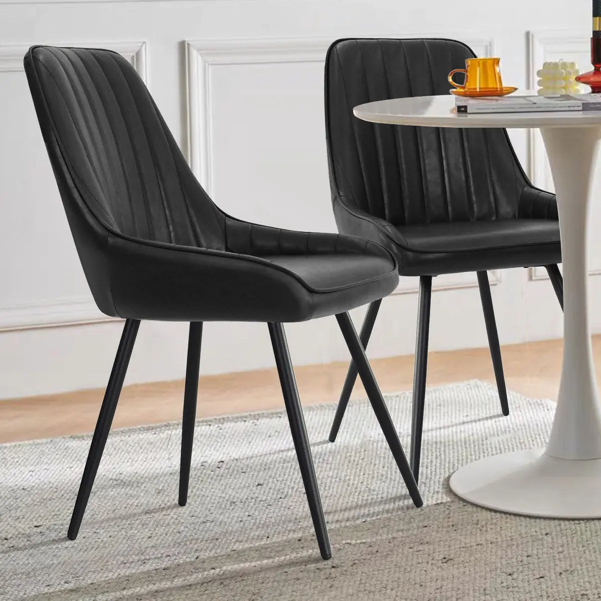 Boston Leather Dining Chair in modern room with white round table and light wood flooring.