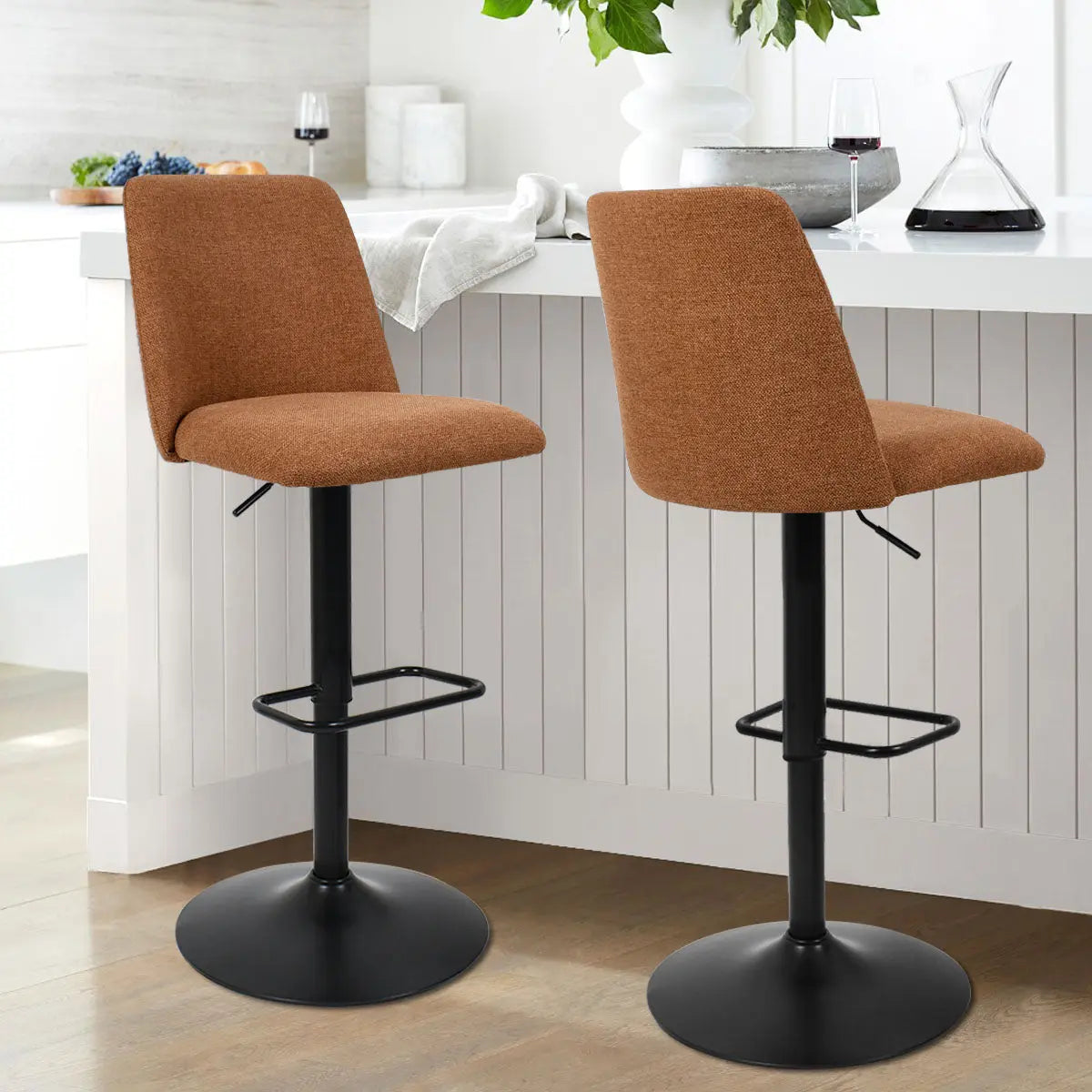 Bruno Stool in kitchen, upholstered brown seat, white cabinets, contemporary decor, light wood flooring.