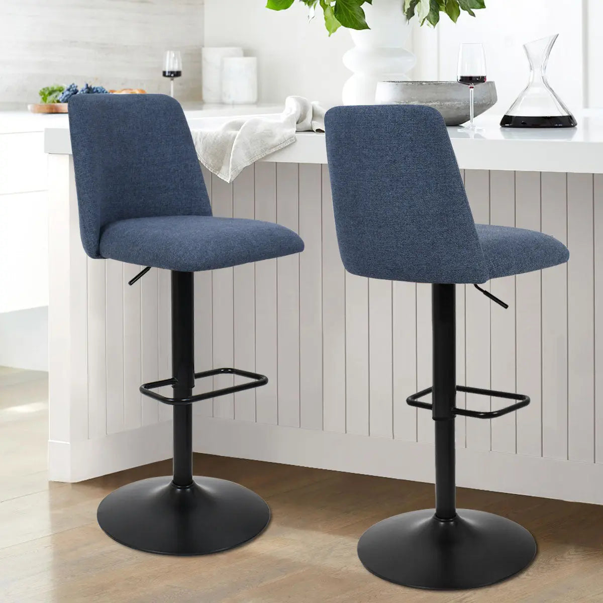 Bruno Modern Upholstered Swivel Adjustable Stool in kitchen with white cabinets and wood flooring.