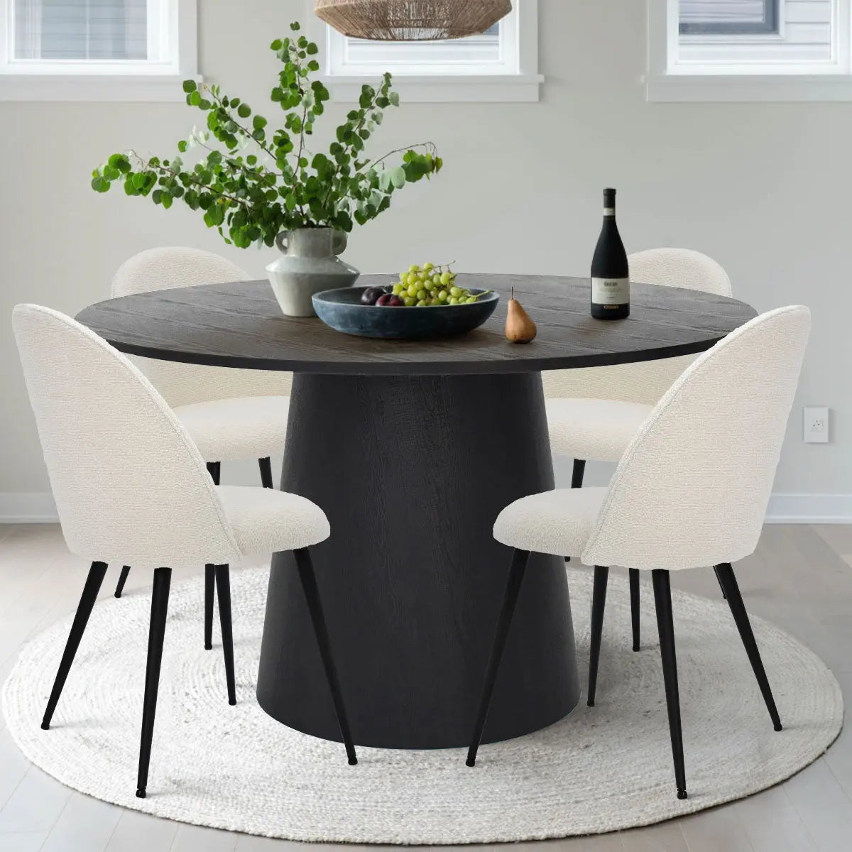 Dwen & Rhon round dining set with black pedestal table and white chairs on rug in dining room.