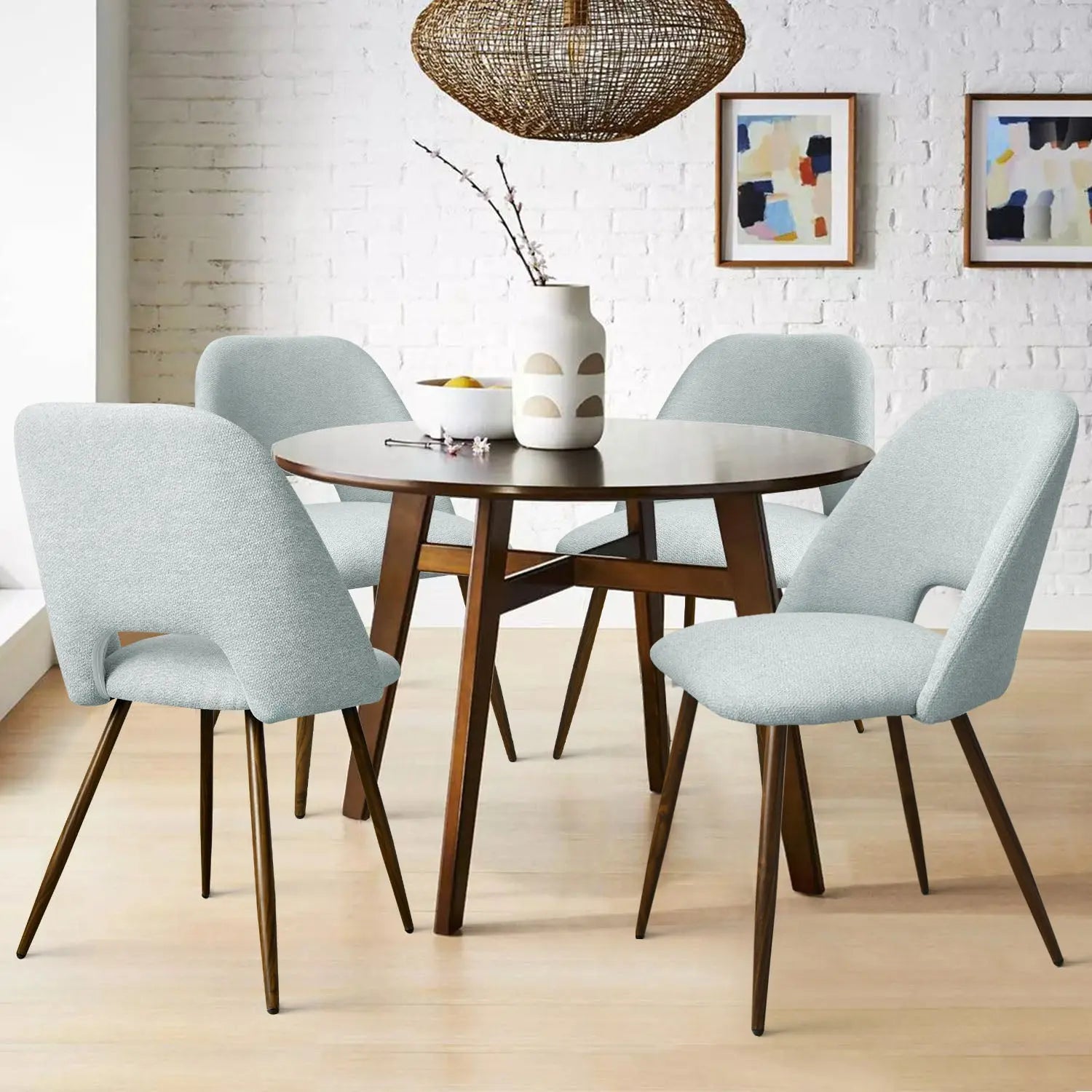 Edwin Boucle Upholstered Dining Chairs in modern room with round wooden table, brick wall, artwork.