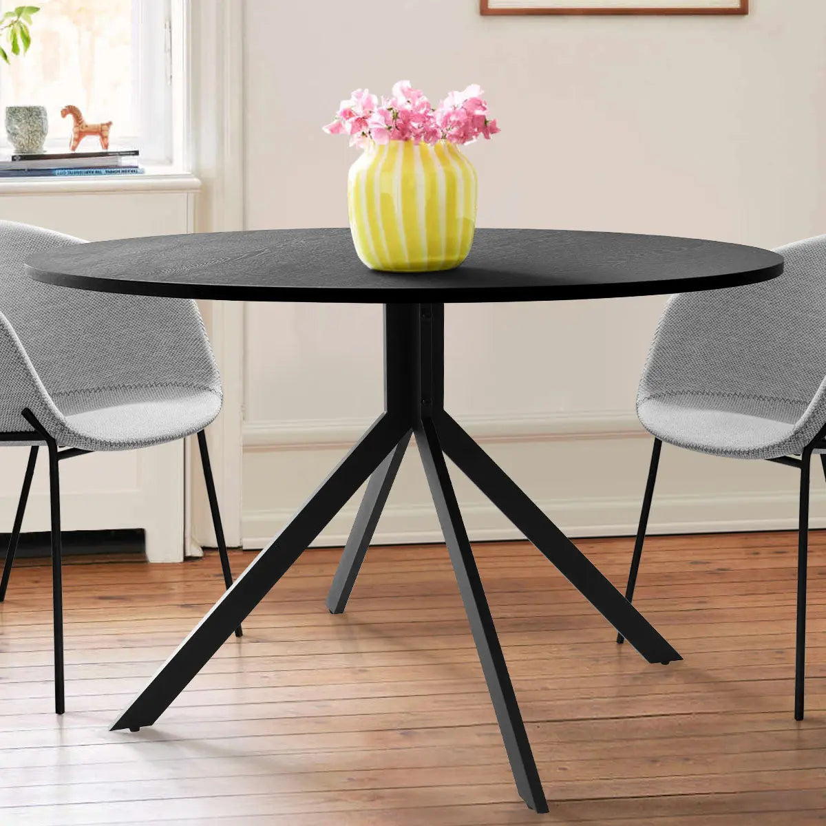 Jones 43" round dining table, black, wooden flooring, gray chairs, modern dining room setup.