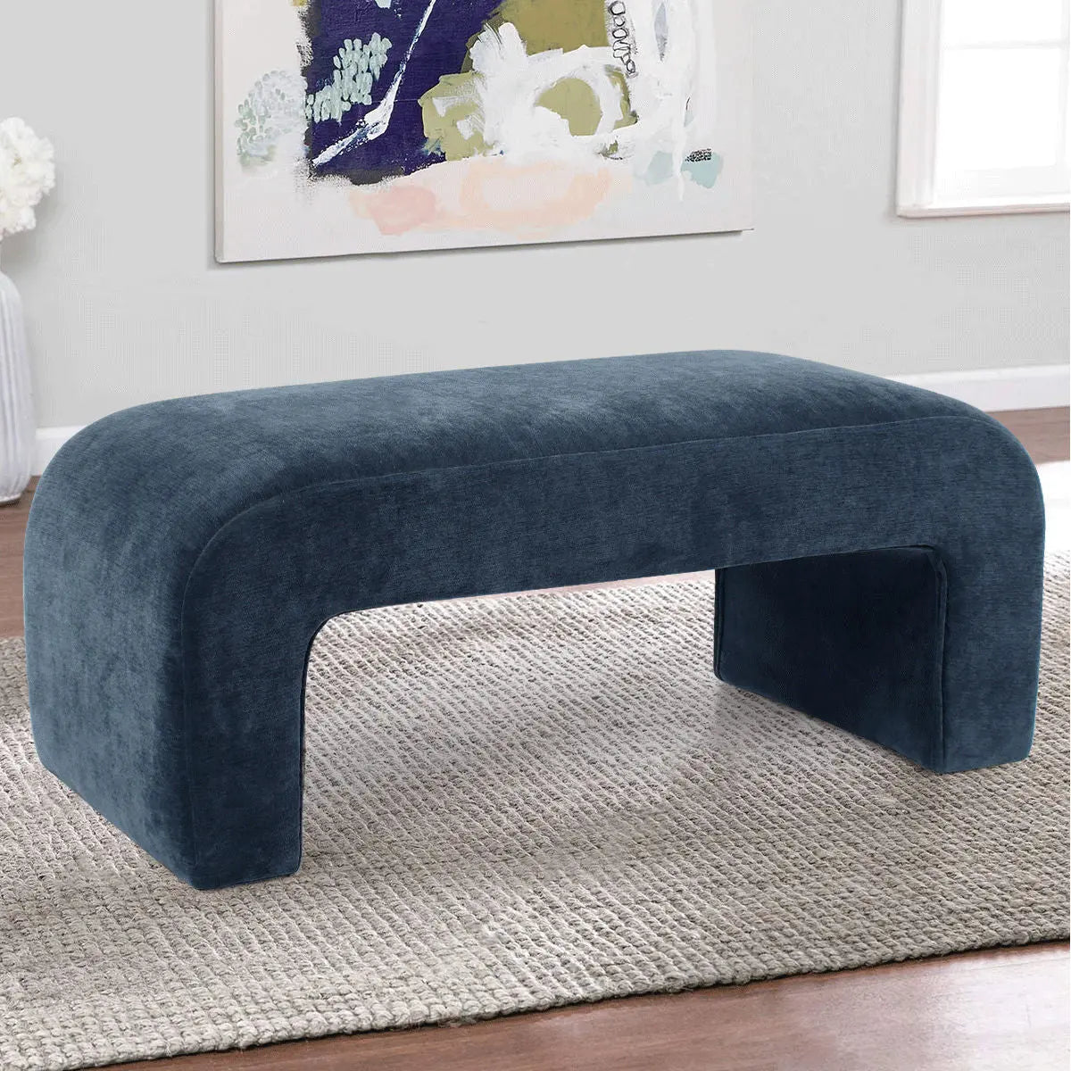 Lily Chenille Waterfall Bench in blue, gray rug, hardwood floors, abstract wall art, modern living room.