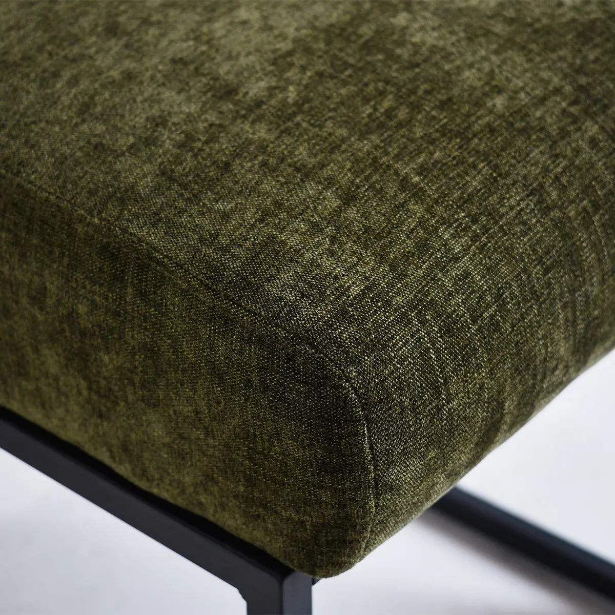 Close-up of Mason Modern Metal Frame Upholstered Dining Chair in dark green fabric with black legs.