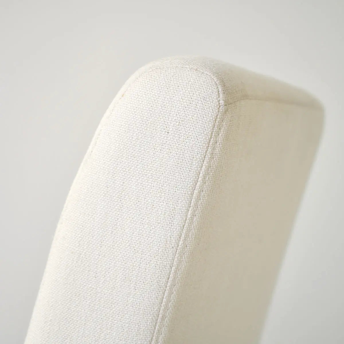 Close-up of North Upholstered Dining Chair in neutral fabric; sleek modern design.