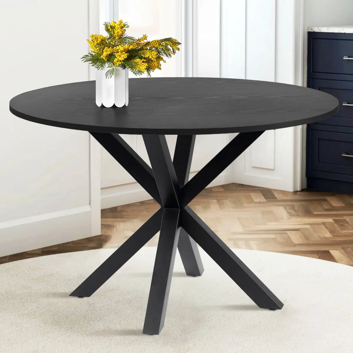 Oliver 39" Modern Round Dining Table in dining area, parquet flooring, white walls, dark cabinetry.